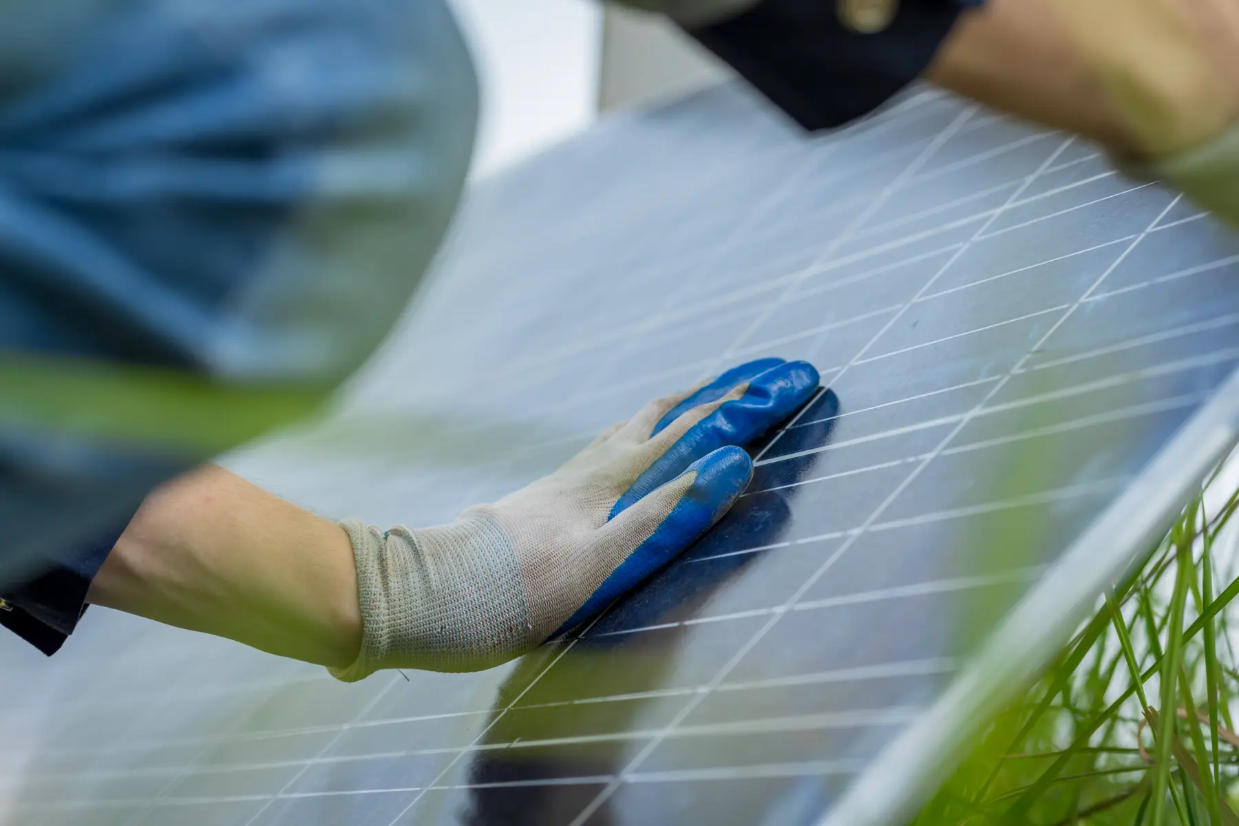 Mano enguantada repasando de cerca la superficie de una placa solar